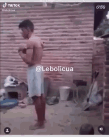 a man without a shirt is standing in front of a brick wall in a tiktok video