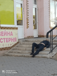 a man laying on a set of stairs in front of a building with a sign that says " beina sterna "