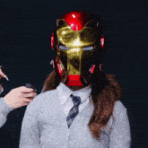 a woman wearing an iron man helmet has a lighter in her hand