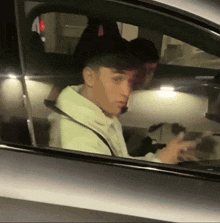 a man in a white hoodie is sitting in a car at night