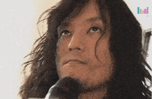 a man with long hair and a beard is looking up at the sky
