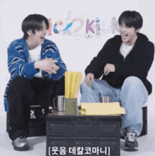 two boys are sitting next to each other and one of them is wearing a blue sweater