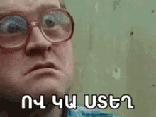 a man wearing glasses is making a funny face and has a foreign language written on his face .