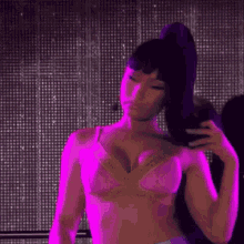 a woman in a pink bra is standing on a stage in front of a pink light .