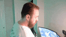 a man with a beard is looking at a computer screen which says ' a ' on it