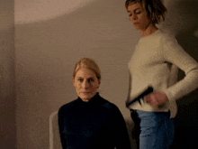 a woman in a white sweater is standing next to a woman in a black shirt
