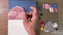 a person is painting a cloudy sky on a canvas with a palette of paint in the background
