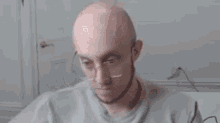 a bald man is making a funny face while sitting in front of a computer .
