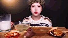 a woman is sitting at a table with a bowl of milk a bowl of food and a glass of milk