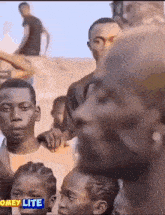 a group of people are standing around a man with the word omey lite on the bottom right corner