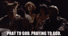 a group of people are standing next to each other in a dark room and praying to god .