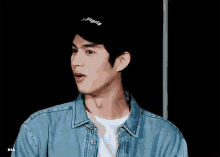a man wearing a palm angels hat and a denim jacket