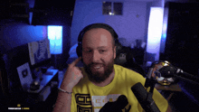 a man with a beard wearing headphones and a yellow shirt that says ' ec ' on it