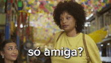 a woman in a yellow shirt is talking to another woman and the words so amiga are above her