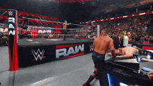 two men are wrestling in a ring with a sign that says raw on it