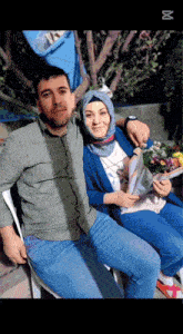 a man and a woman are posing for a picture and the woman is holding flowers