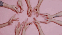a group of people are making a peace sign with their hands on a pink background .