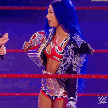 a woman with blue hair is wearing a wrestling ring belt with the letter w on it