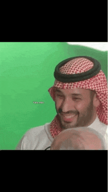a man in a turban is smiling in front of a green background .