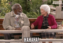 a man and a woman sit on a bench with a sign that says tv land