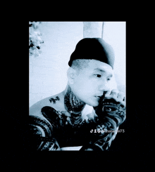 a man with glasses and a tattoo on his head is sitting on the floor .
