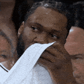 a man with a beard wipes his face with a towel