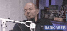 a man sitting in front of a microphone with the words dark web on the bottom right