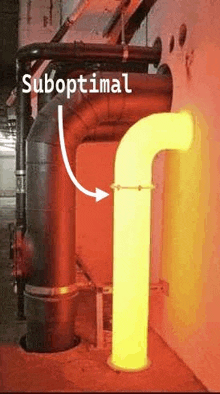 a yellow pipe is coming out of a hole in a wall next to a red pipe .