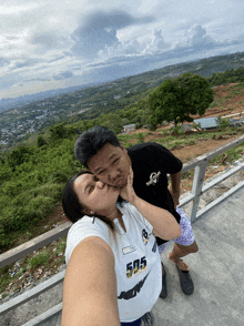 a man kisses a woman who is wearing a shirt that says 505 on it