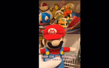 a stuffed mario is standing in front of a shelf full of stuffed animals