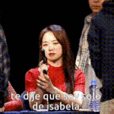 a woman in a red shirt is holding a microphone and says te dije que soy solo de isabela