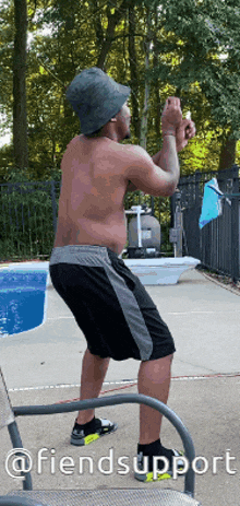 a shirtless man wearing a bucket hat is squatting in front of a pool with the words " @fiendsupport " below him