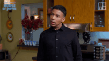 a man in a black shirt is standing in a kitchen with the words merry 's house of payne on the wall behind him