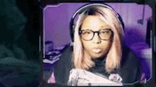 a woman with pink hair and glasses is sitting in front of a computer screen .
