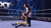 two women are wrestling in a ring with the word xt on the wall behind them