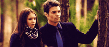 a man and a woman standing next to each other in the woods