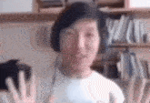 a man wearing headphones is giving a high five while sitting in front of a bookshelf .