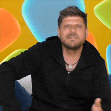 a man with a beard wearing a black jacket with the word adidas on the front