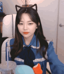 a girl wearing a cat ear headband sits in a chair with a cup of coffee