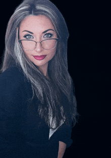 a woman wearing glasses and a black sweater looks at the camera