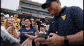 a man wearing a mountaineers shirt talks to a crowd of people