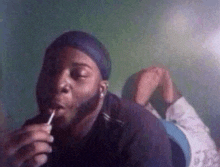 a man is smoking a cigarette while laying on his stomach on a bed .