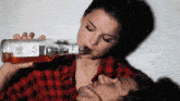 a woman drinking from a bottle that says jim beam on it