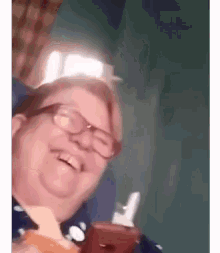 a man wearing glasses is holding a bottle of ketchup and smiling .