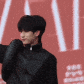 a man in a black jacket is standing on a red background