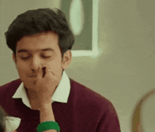 a man is sitting at a table with a woman applying henna to his nose .