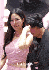 a woman in a pink dress is standing next to a man wearing headphones and a sign that says lily rosi 38