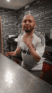 a man wearing a bwin shirt stands in front of a blackboard