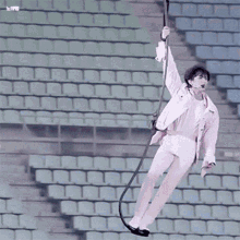 a person is hanging from a rope in front of a stadium .