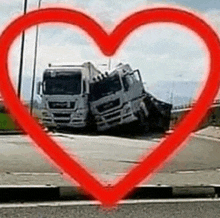 a red heart is surrounding two trucks that have crashed into each other on the side of the road .